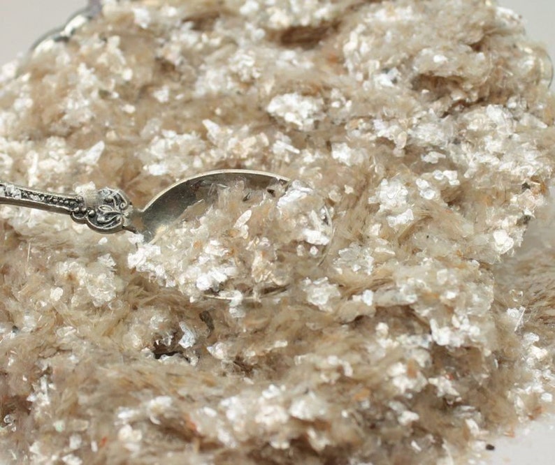 Peut inclure: Gros plan sur un tas de paillettes de mica, un mat&eacute;riau chatoyant et iris&eacute; souvent utilis&eacute; dans l'artisanat et les cosm&eacute;tiques. Les paillettes sont de couleur beige clair avec un reflet argent&eacute;.