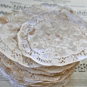 May include: A stack of white lace doilies with a delicate floral pattern. The doilies are arranged on a sheet of music.