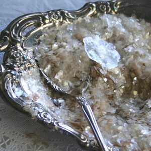 Peut inclure: Un plat de service en argent avec des d&eacute;tails orn&eacute;s rempli de paillettes blanches iris&eacute;es. Une cuill&egrave;re en argent est partiellement immerg&eacute;e dans les paillettes.