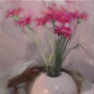 May include: A still life painting of a white spherical vase holding a bouquet of bright pink flowers with green stems. The vase sits on a table, with a blurred chair in the background. The painting has a soft, diffused light.