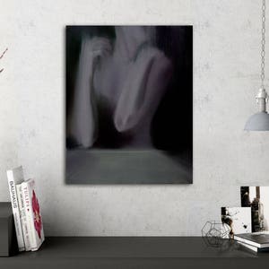 May include: An abstract painting on canvas depicts a blurred figure in shades of gray and purple. The artwork is mounted on a white wall, with a minimalist white vase, books, and a hanging lamp in the scene.