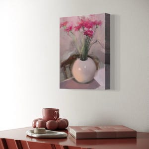 May include: A still life painting of pink flowers in a white vase. The painting is mounted on a wall above a red cabinet. A matching red cup and decorative tray are on the cabinet.
