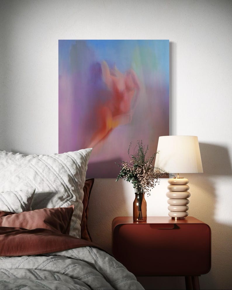 K&ouml;nnte beinhalten: Schlafzimmer-Interieur mit einem abstrakten Gem&auml;lde in Rosa-, Lila- und Blaut&ouml;nen. Ein Nachttisch mit einer Lampe und einer Blumenvase steht neben einem Bett mit Kissen und einer Bettdecke.