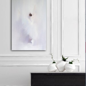 May include: An abstract painting of a dancer in a white dress, with soft, blurred brushstrokes. The artwork is displayed on a white wall above a black and white cabinet. Three white, textured vases with greenery are on the cabinet.