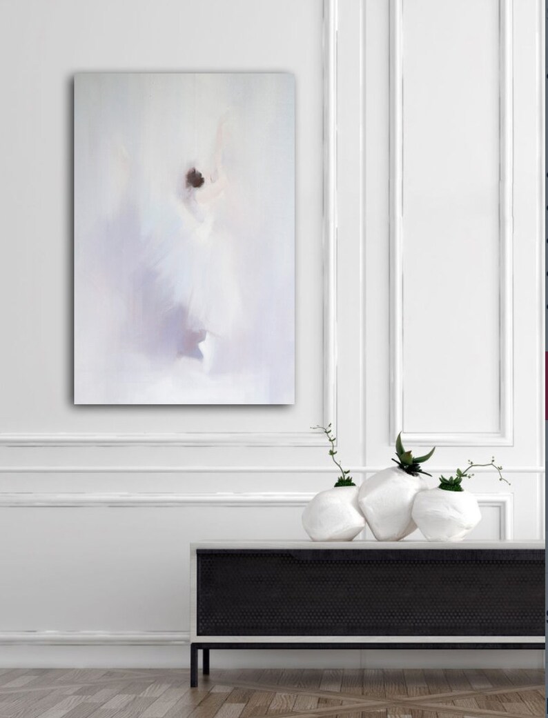 May include: An abstract painting of a dancer in a white dress, with soft, blurred brushstrokes. The artwork is displayed on a white wall above a black and white cabinet. Three white, textured vases with greenery are on the cabinet.