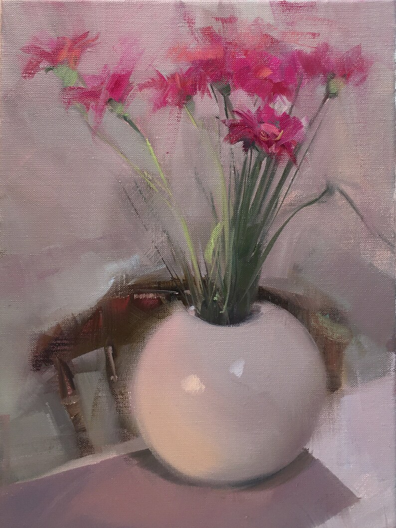 May include: A still life painting of a white spherical vase holding a bouquet of bright pink flowers with green stems. The vase sits on a table, with a blurred chair in the background. The painting has a soft, diffused light.