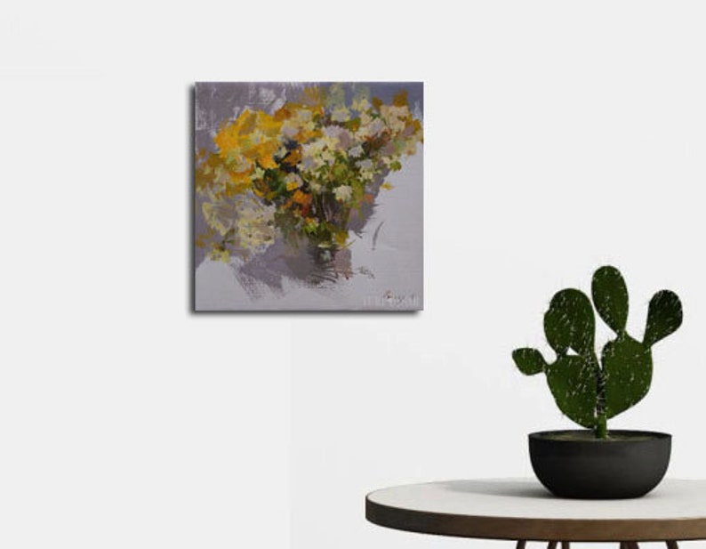 Op de afbeelding: Een olieverfschilderij op canvas toont een boeket gele en witte bloemen in een vaas. Het kunstwerk heeft een textuurrijke, impressionistische stijl met zichtbare penseelstreken. De achtergrond is zachtgrijs en het schilderij wordt op een witte muur getoond.