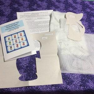 May include: A LanethsQuilt Kits Overall Sam quilt pattern set including printed instruction sheets, a paper guide labelled Guide A, a paper guide labelled Guide B, and translucent interfacing sheets with printed shapes for quilt assembly.