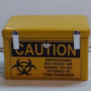 May include: Yellow metal box with a biohazard symbol and the text "CAUTION BIOHAZARD NO FOOD OR DRINK TO BE STORED IN THIS FREEZER".