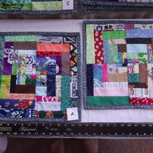 May include: Three handmade patchwork quilt squares with a variety of colorful fabrics. The squares are labeled A, B, and C. The squares are made of different colors and patterns, including red, blue, green, brown, and white.