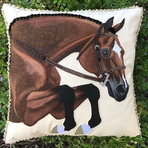 May include: A brown and white horse with a black bridle jumps over a white pillow with a brown border. The horse is depicted in a realistic style.