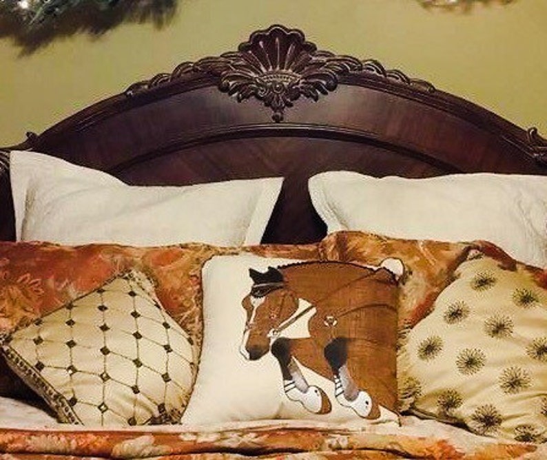 May include: A bed with a brown headboard and a white, brown, and gold patterned bedding set. The bedding includes a pillow with a horse jumping over a fence.