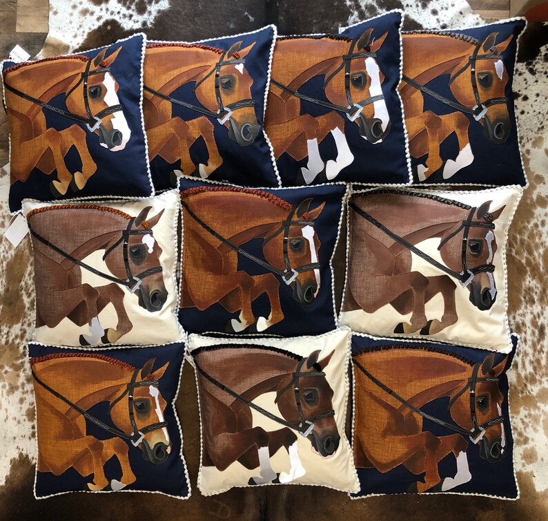 May include: Nine decorative throw pillows featuring a brown and white horse design. The pillows have a navy blue background and white trim.
