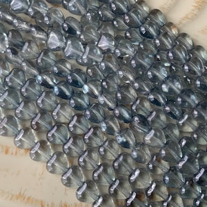 May include: A strand of light blue glass heart beads. The beads are translucent and have a slightly iridescent finish.