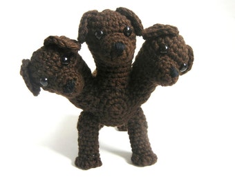 May include: A brown crocheted three-headed dog toy with black eyes.