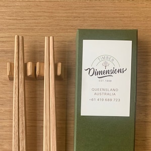Peut inclure: Une paire de baguettes en bois dans une boîte verte avec le texte "Timber Dimensions Est. 1998 Queensland Australia +61 419 689 723"