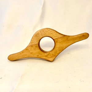 May include: A wooden book page holder with a circular cutout in the centre. The holder is light brown and has a smooth, polished finish.