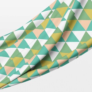 May include: A fabric with a geometric pattern of green, yellow, peach, and white triangles.