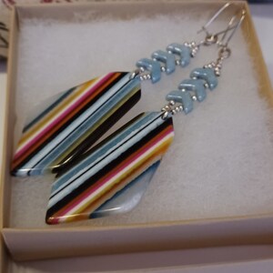 May include: A pair of silver earrings with blue and white chevron beads and colorful striped agate pendants.