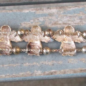 May include: A silver-toned bracelet featuring six angel charms with outstretched wings. The bracelet has a delicate chain design with small beads between the angel figures. The clasp is a simple bar and loop closure.