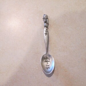 May include: A silver spoon with a Precious Moments figurine on the handle. The bowl of the spoon has the words "Jesus is the light" engraved on it.