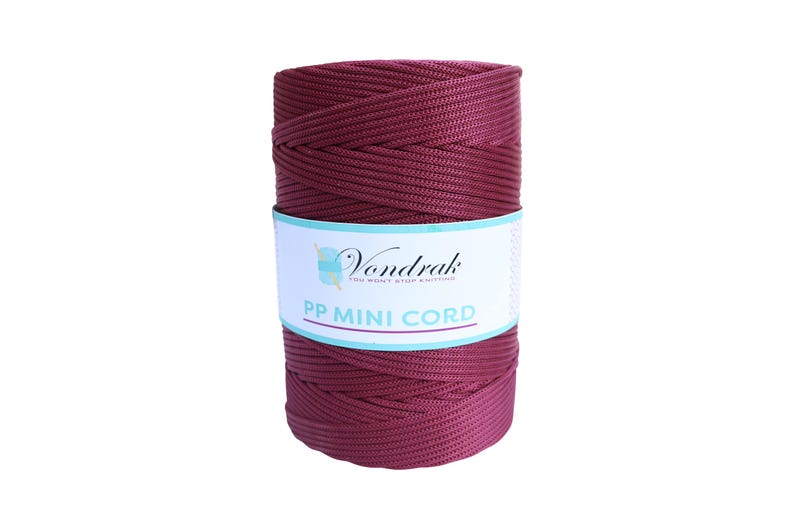 May include: A spool of burgundy PP Mini Cord by Vondrak. The cord is tightly wound and wrapped with a white label featuring the brand name and product details. The cord is a solid, rich burgundy color.