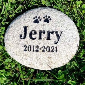 May include: A gray stone memorial with two paw prints and the inscription "Jerry 2012-2021".