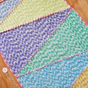 May include: A colorful crochet blanket with a chevron pattern in shades of blue, green, purple, yellow, and pink. The blanket is edged with a pink crocheted border.