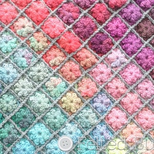 May include: A close-up of a crocheted blanket with a diamond pattern. The blanket is made with a variety of colours, including pink, purple, blue, and green. The blanket is made with a textured stitch that creates a raised flower pattern.