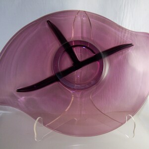 May include: A purple glass serving dish with three divided sections. The dish has a wavy edge and a clear glass base.
