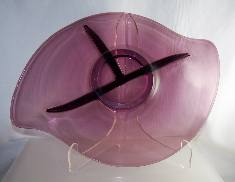 May include: A purple glass serving dish with three divided sections. The dish has a wavy edge and a clear glass base.