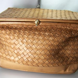 May include: A tan leather shoulder bag with a woven design. The bag features a rectangular shape with a flap closure and a long shoulder strap. The bag's exterior has a basket weave pattern.