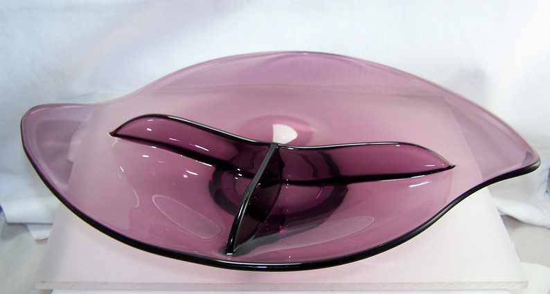 May include: A purple glass serving dish with three divided sections. The dish has a wavy edge and a slightly raised center.