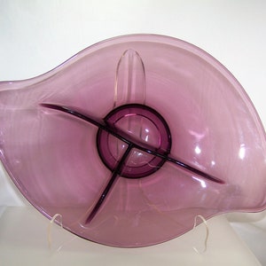 May include: A purple glass serving dish with three divided sections. The dish is shaped like a leaf and has a wavy edge.