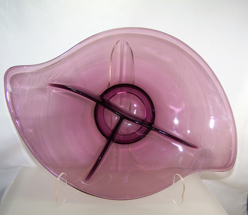 May include: A purple glass serving dish with three divided sections. The dish is shaped like a leaf and has a wavy edge.