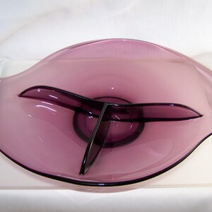 May include: A purple glass serving dish with three divided sections. The dish has a wavy, organic shape.