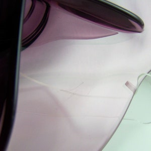 May include: A close-up of a purple glass bowl with a white string attached to the rim.