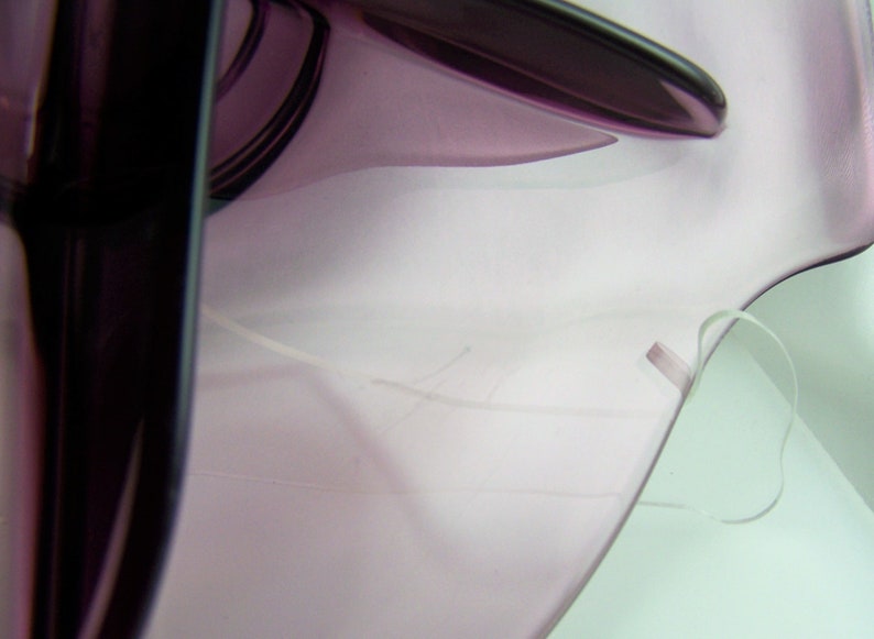 May include: A close-up of a purple glass bowl with a white string attached to the rim.