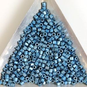 May include: A pile of small, square, metallic blue beads in a triangular tray. The beads have a shiny, metallic finish.