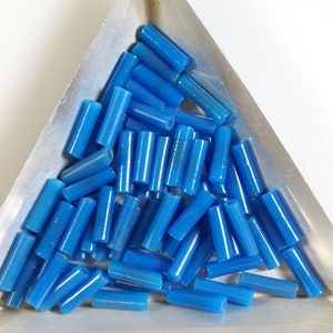 May include: A pile of small, bright blue glass tubes, likely for jewelry making or crafting.