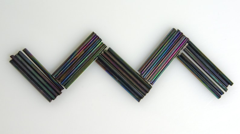May include: A zig-zag pattern made of iridescent black glass rods.