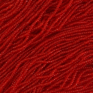 May include: A close-up of a large quantity of red seed beads. The beads are small and round, and they are arranged in a random pattern. The beads are shiny and have a slight sparkle to them.