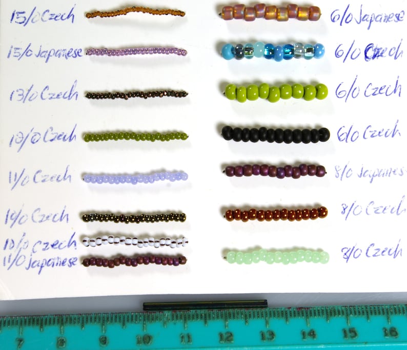May include: A close-up of a white surface with rows of different colored beads. The beads are arranged in pairs, with each pair labeled with a size and type of bead. The sizes range from 6/0 to 15/0, and the types are Czech and Japanese.