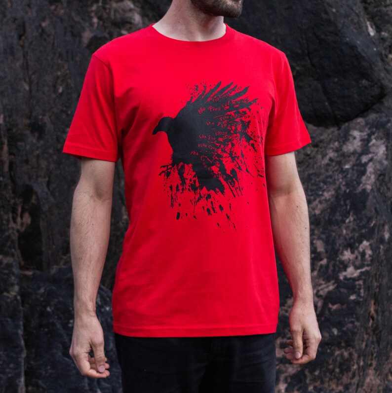 May include: Red t-shirt with a black silhouette of a raven with splatter paint design. The raven has text on it that says "The flow is the way".