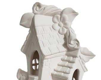 May include: A white ceramic fairy house with a textured roof, arched windows, and floral accents. The whimsical design features a double door entrance and is suitable for decorative purposes.
