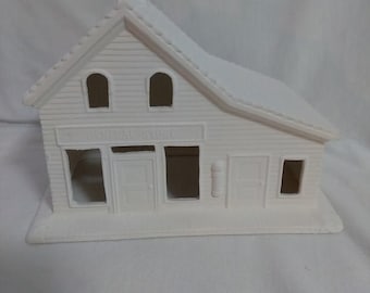 May include: White ceramic unpainted model of a small general store building with a sign that reads "The General Store".