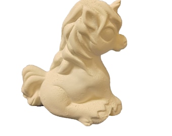May include: A white ceramic unicorn figurine with a curled mane and tail. The unicorn is sitting with its head turned to the side.