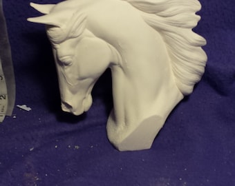 May include: White ceramic horse head sculpture with a flowing mane. The sculpture is in a profile view with the horse's head tilted down.