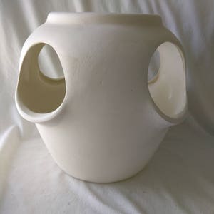May include: White ceramic planter with three large circular openings. The planter is round and has a smooth, matte finish.