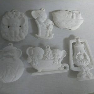 May include: Set of six white ceramic Christmas ornaments featuring various winter themes, including a snowman, a sleigh with reindeer, a lantern, and a mouse family.